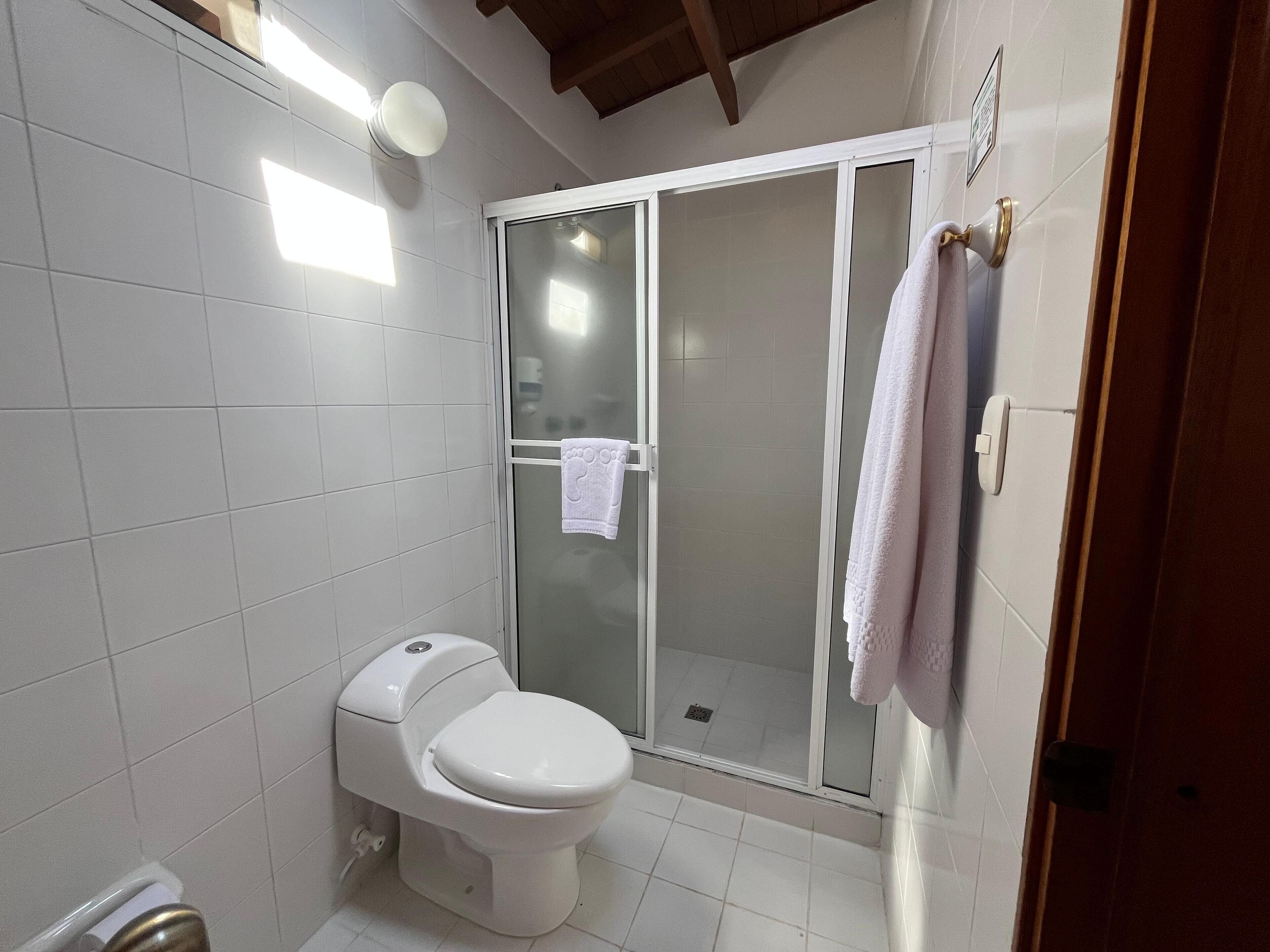 Ein Badezimmer mit Toilette, einer Duschkabine aus Glas und einem Handtuch an der Wand.