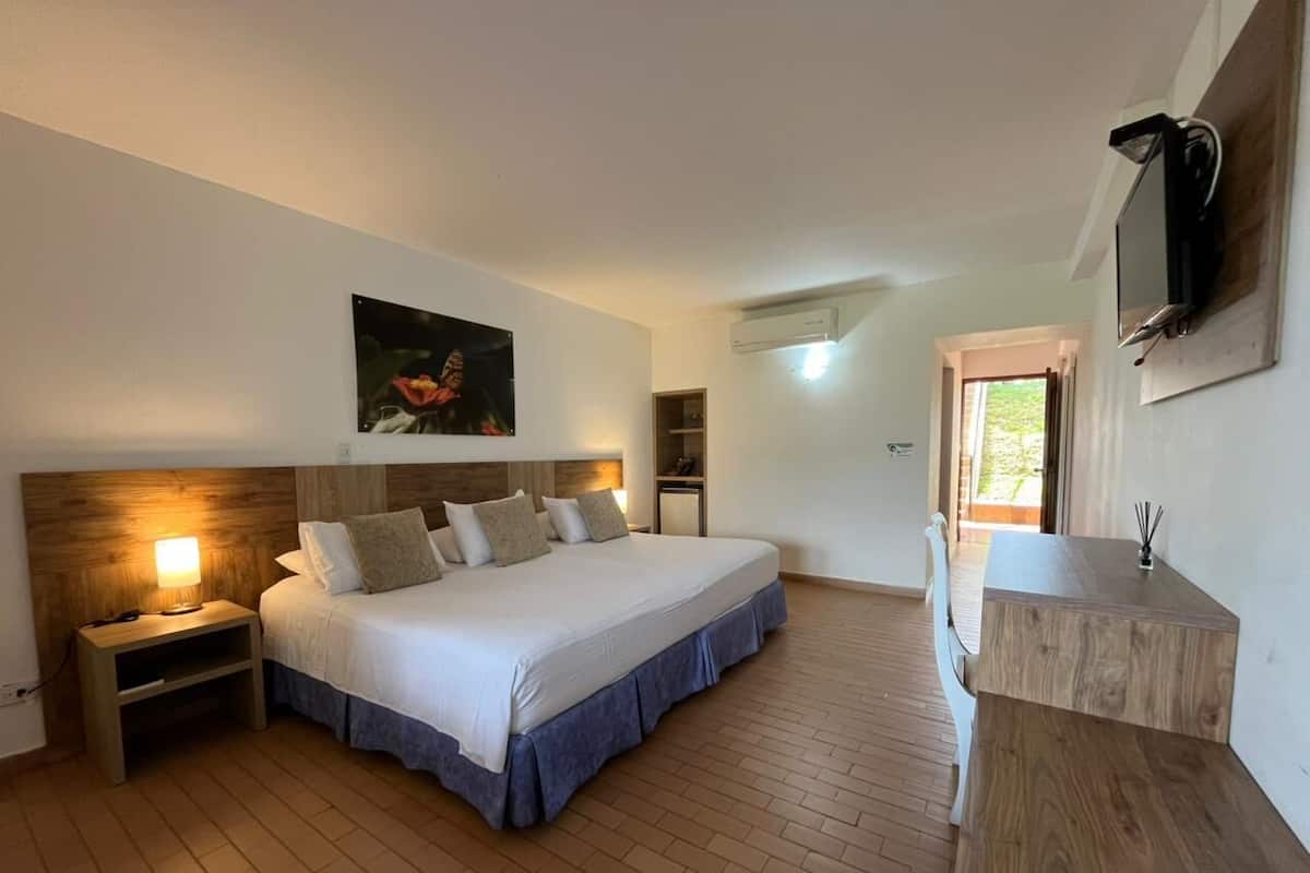 Une chambre à coucher comprenant un lit, une table de chevet, une lampe et un téléviseur fixé au mur.