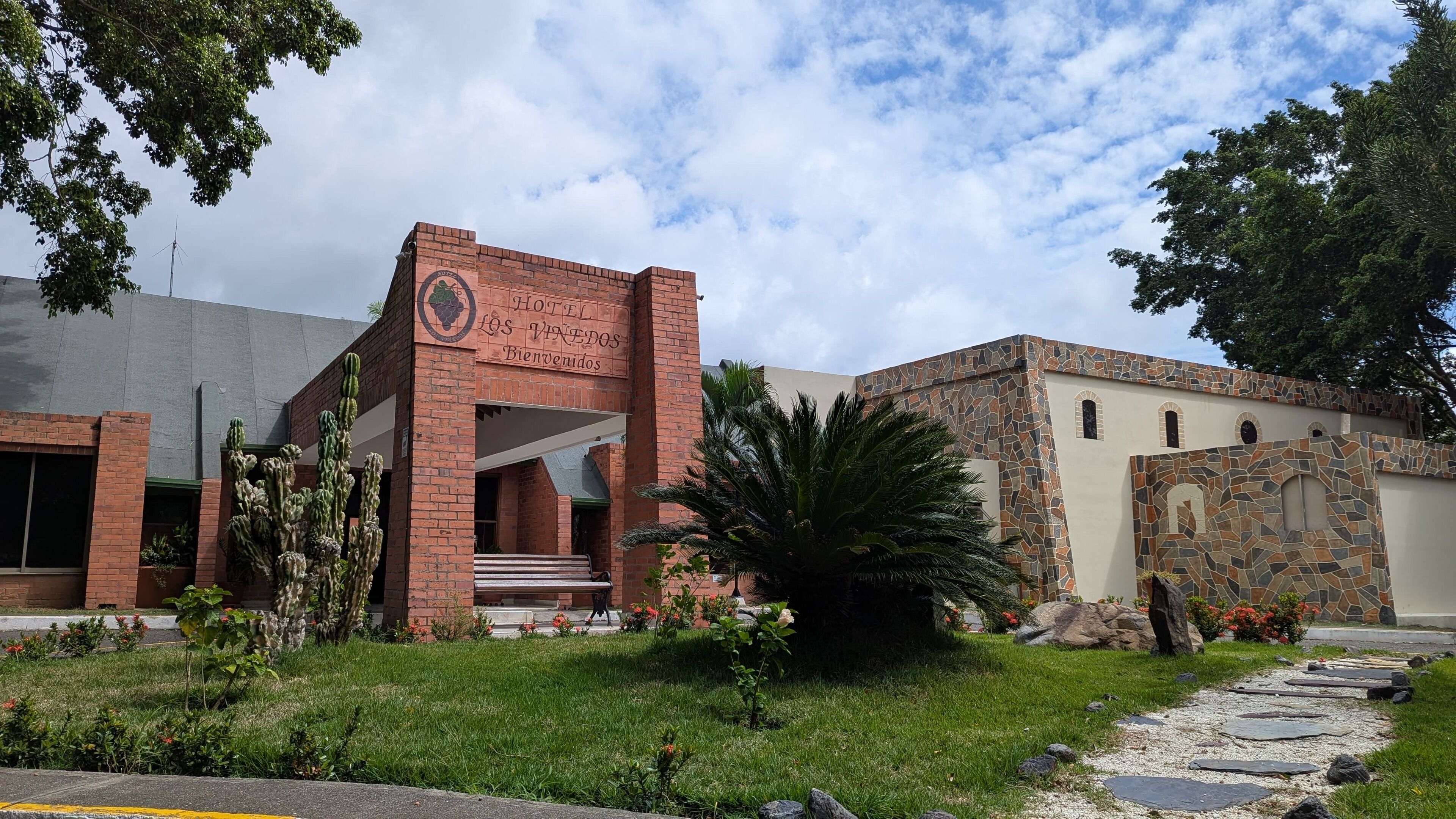 A hotel entrance with a brick facade, a stone wall, and a cactus garden.