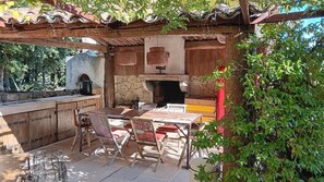 Enjoy al fresco dining in a serene outdoor setting surrounded by lush greenery and a pergola.