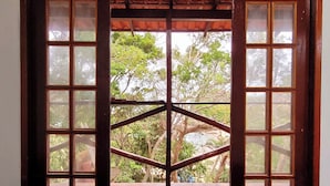 Une pièce dotée d’une grande porte en bois donnant sur un espace extérieur, d’un tapis bleu et offrant une vue sur des arbres et une structure en bois.