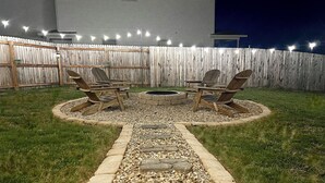 A backyard with a fire pit, stone pathway, and outdoor furniture. - 🤍Modern Alamo City Retreat🤍 (San Antonio)