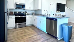 A modern kitchen with white cabinets, stainless steel appliances, a granite countertop, and a built-in dishwasher. - 🤍Modern Alamo City Retreat🤍 (San Antonio)