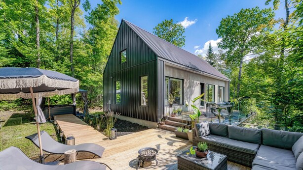 Una casa moderna con terraza, mobiliario exterior y un pozo de fuego.