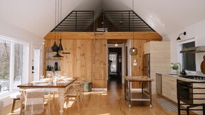 Una cocina amplia con detalles de madera, un comedor con mesa dispuesta para cuatro personas, y vistas al exterior.