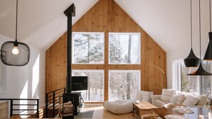 Un interior acogedor de cabaña con un gran muro de madera, una chimenea, un sofá y un comedor.