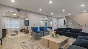 A modern living room with a sofa, armchairs, a coffee table, and a TV.