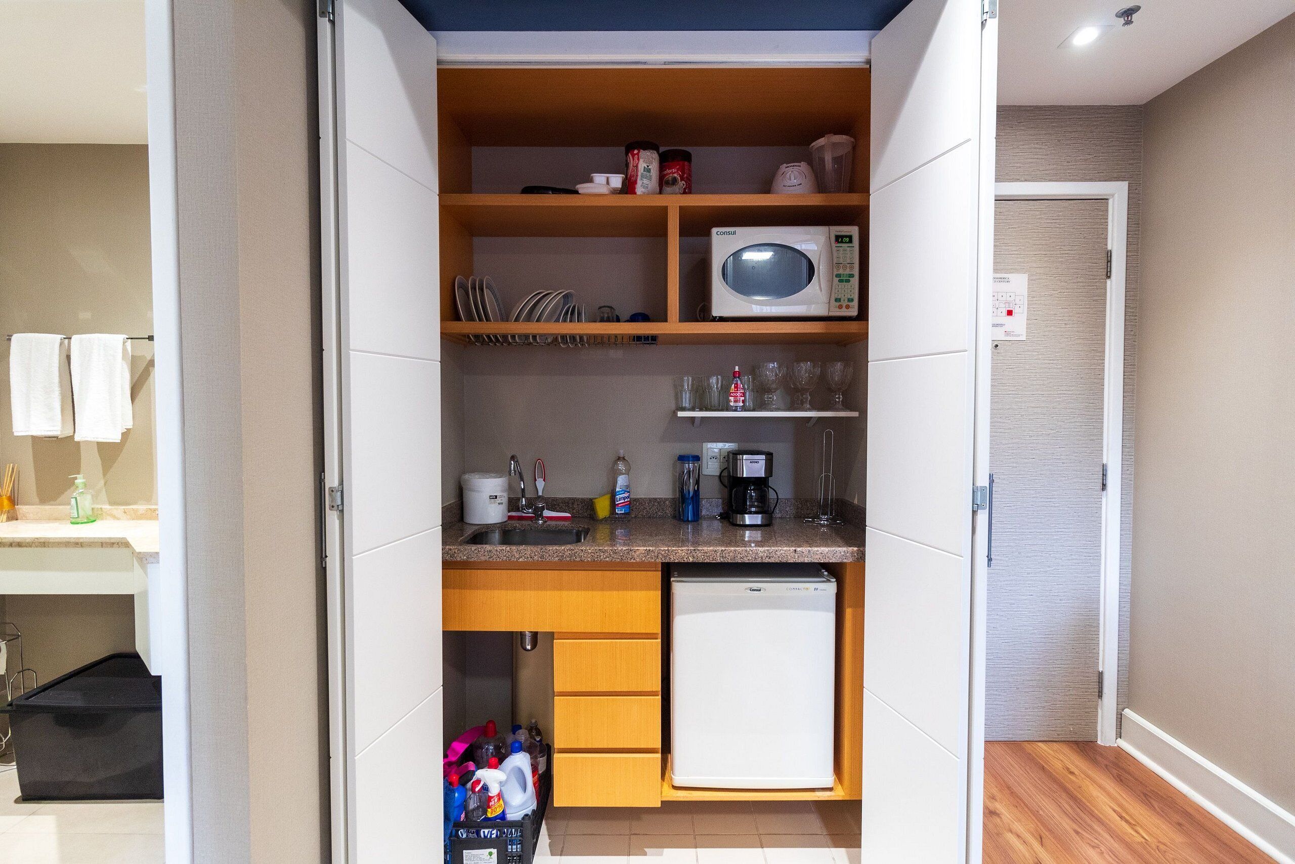 A compact kitchen with a microwave, coffee maker, and storage cabinets.