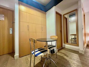 A small room with a round table and two chairs, a wooden cabinet, and a mirror on the wall. - LFlats Hotel Alameda Lorena Jardins (S ão Paulo)