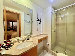 A modern bathroom with a large mirror, a sink, and a glass shower enclosure. - LFlats Hotel Alameda Lorena Jardins (São Paulo)