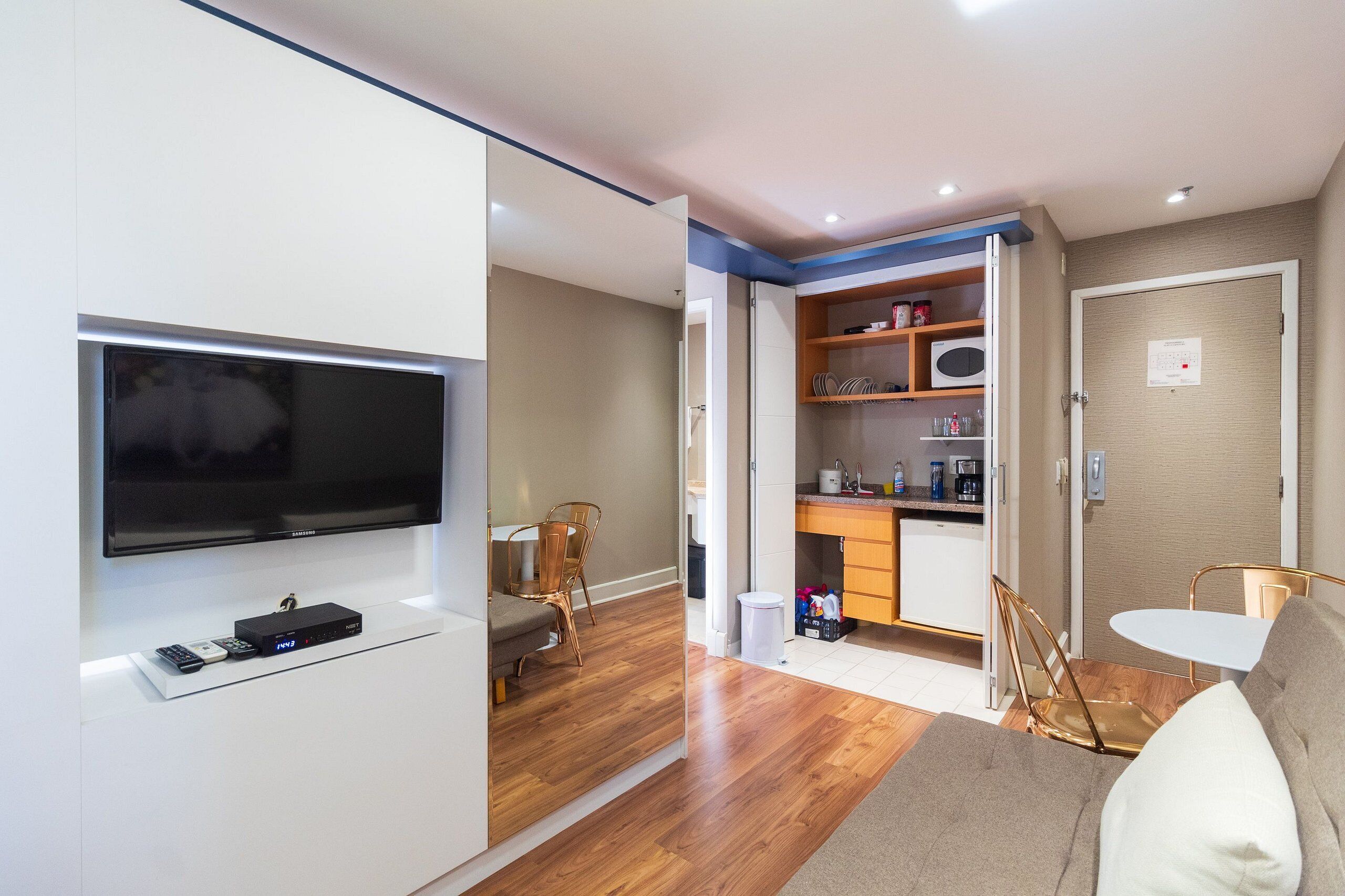 Un espace de vie compact comprenant un téléviseur à écran plat, une kitchenette, un coin repas et un canapé.