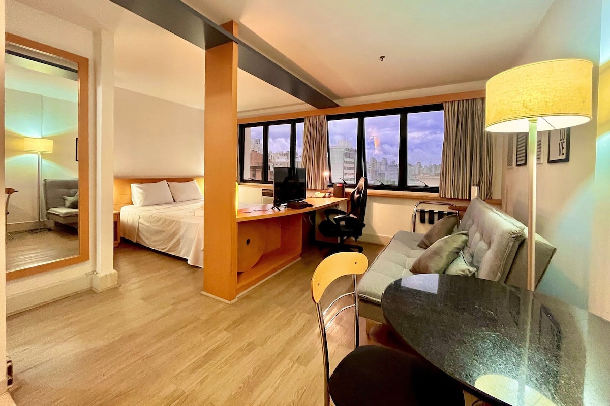 Una habitación de hotel con cama, escritorio, silla y mesa de comedor.