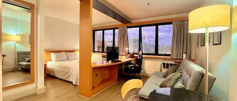 A hotel room with a bed, desk, chair, and a dining table.