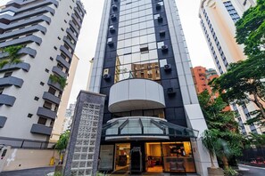 Un hôtel moderne doté d’une entrée en verre, de plusieurs étages et d’un atrium central.