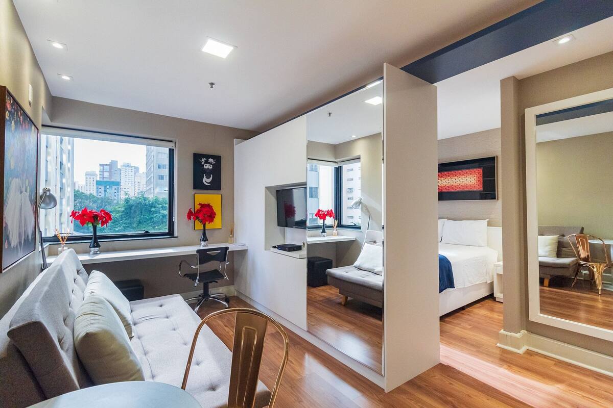Una habitación de hotel moderna con sofá, escritorio, televisión y cama.