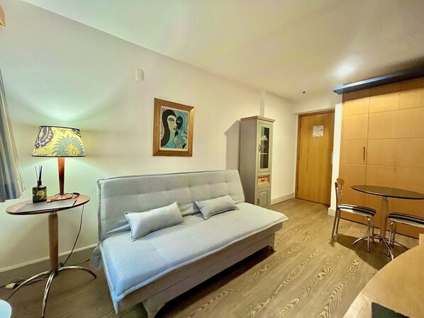 Une pièce comprenant un lit, une petite table avec une lampe, une armoire et une porte.