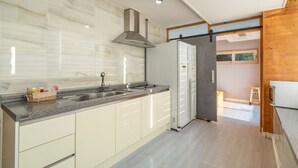 Eine moderne Küche mit Marmorfliesenspiegel, Edelstahlgeräten und einer Schiebetür aus Holz, die in einen anderen Raum führt.