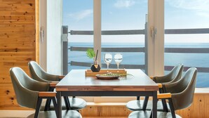 Un coin repas avec une table dressée pour deux personnes, deux verres à vin, une bouteille d’eau et une petite plante.