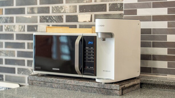 A Samsung microwave on a granite countertop with a water dispenser beside it. - Geoje Inbito Pension (Geoje)