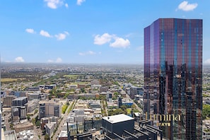 A high-rise hotel with a modern glass facade, surrounded by a cityscape. - Lumina Stays - Victoria One (Melbourne)