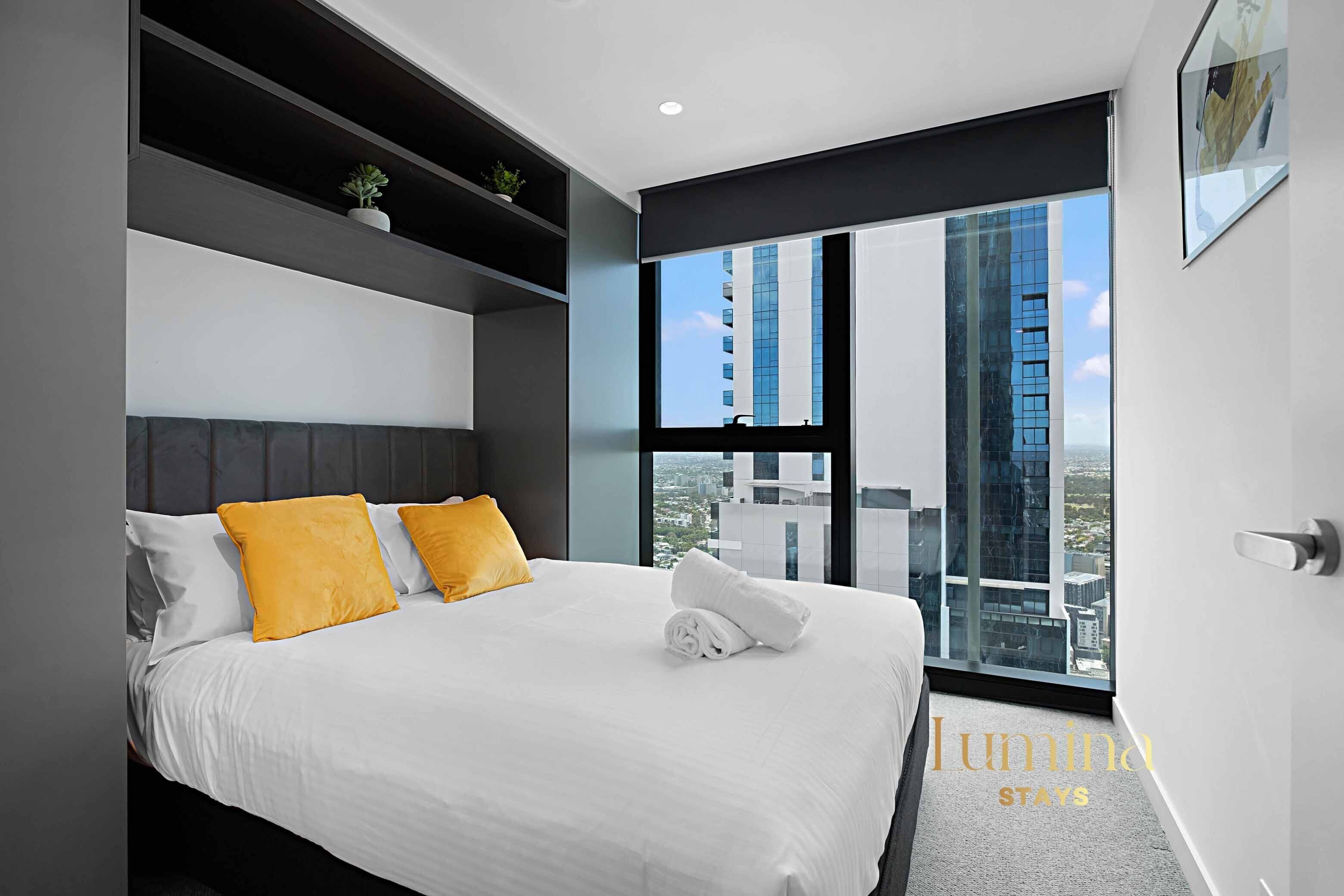 Una habitación de hotel moderna con una cama grande, vistas a la ciudad y un diseño minimalista.
