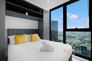 A modern hotel room with a large bed, a city view, and a minimalist design. - Lumina Stays - Victoria One (Melbourne)