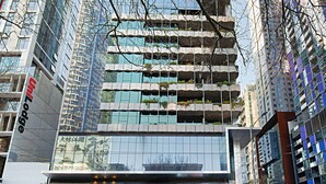 Ein modernes Gebäude mit mehreren Balkonen, großen Fenstern und einer Fassade aus Glas und Beton.