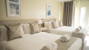 A hotel room with two beds, each with a geometric-patterned headboard, white linens, and rolled towels. - Casa Marta Hotel (Iloilo)