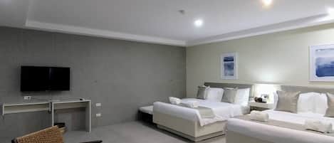 Una habitación de hotel moderna con dos camas, un televisor de pantalla plana, un escritorio y una zona de estar con sillas de mimbre.