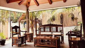 A covered outdoor seating area with wooden furniture and a ceiling fan. - Casa Marta Hotel (Iloilo)