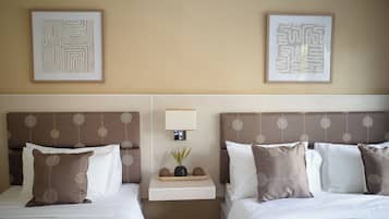 Ein Hotelzimmer mit zwei Betten, einem Nachttisch und zwei gerahmten Kunstwerken an der Wand.