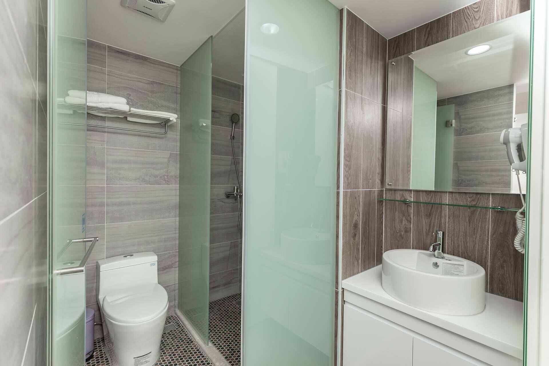 Une salle de bain moderne avec une douche à parois de verre, des toilettes blanches et un lavabo avec un miroir au-dessus.