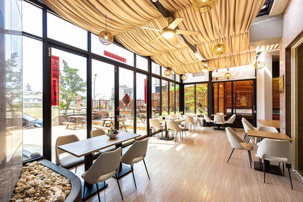 A modern restaurant interior with large windows, wooden tables, and chairs. - SDK-Hotel (Magong)