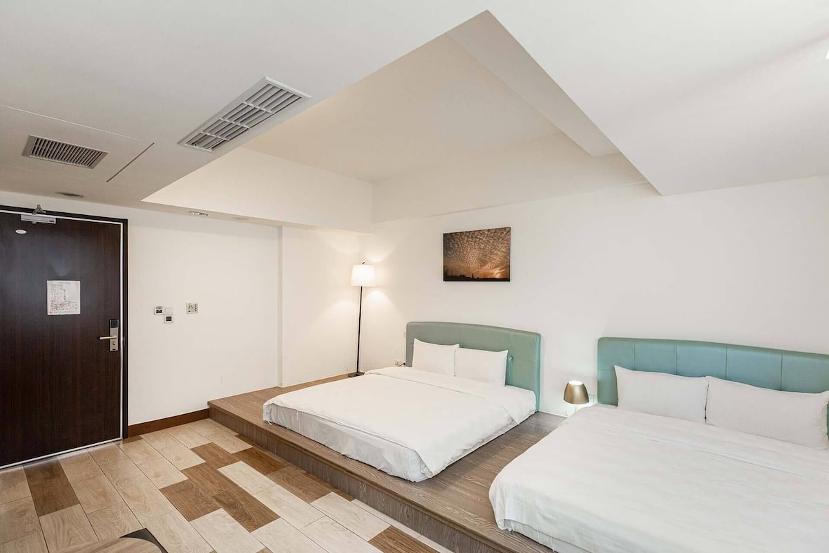 Ein Hotelzimmer mit zwei Betten, Holzboden, einer Tür mit einer Karte und einem Wandbild des Nachthimmels.