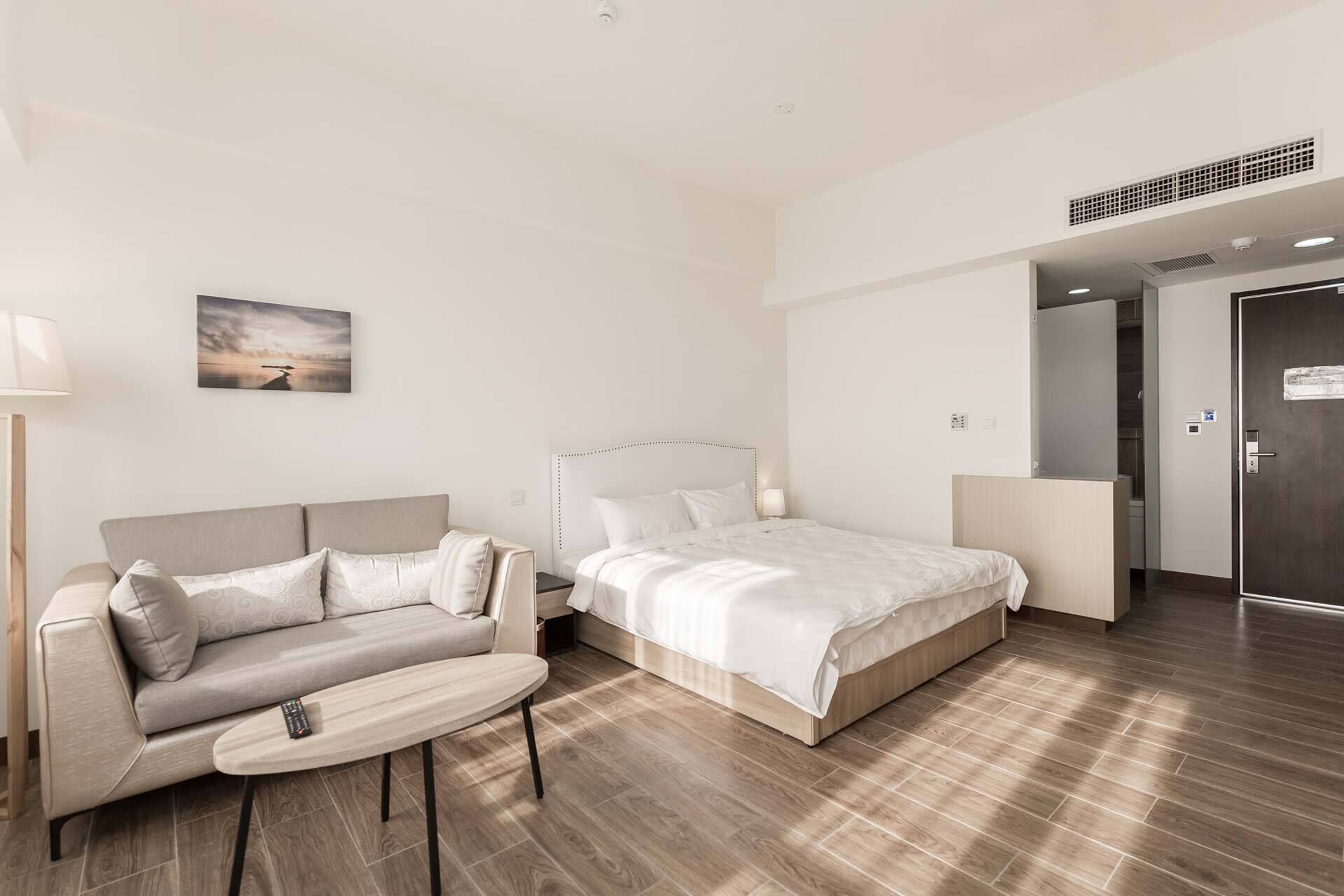 Ein modernes Hotelzimmer mit einem Bett, einer Couch, einem kleinen Tisch und einem Gemälde an der Wand.