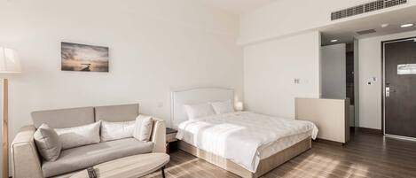 Ein modernes Hotelzimmer mit einem Bett, einer Couch, einem kleinen Tisch und einem Gemälde an der Wand.
