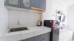 Eine Küche mit Spüle aus Edelstahl, einem Wasserkocher und einem Kühlschrank.