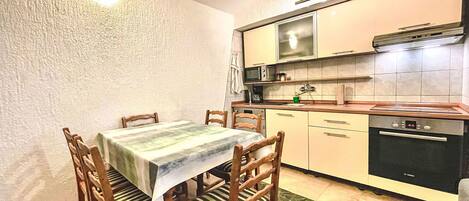 A compact kitchen with a dining table, chairs, and basic appliances.
