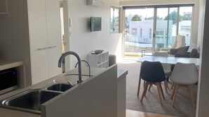 Eine moderne Küche mit integrierter Kochinsel, einem Essbereich mit Stühlen und einem großen Fenster mit Blick auf die Stadt.