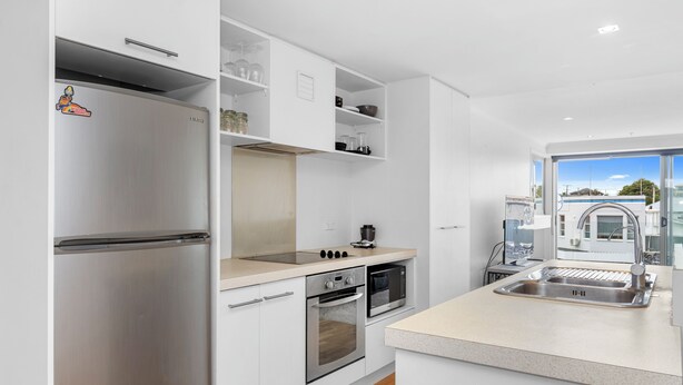 Eine moderne Küche mit Edelstahlgeräten, weißen Schränken und einem großen Fenster mit Blick nach außen.