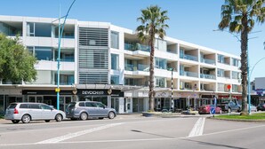 Ein mehrstöckiges Hotel mit Balkonen, einem Parkplatz und Palmen.
