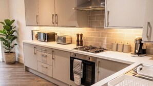 A modern kitchen with stainless steel appliances, a built-in oven, and a countertop with a coffee maker. - 2 Bed, Sleeps 4, Pet Friendly, Free Parking (Rotherham)