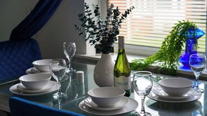 Een eettafel gedekt met witte kommen en wijnglazen, een fles VinaSol wijn, en een vaas met groene planten.