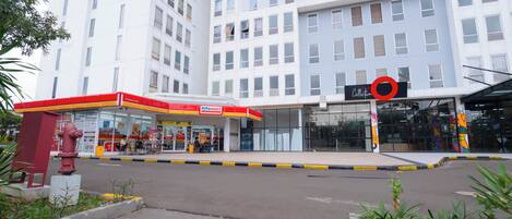 A modern building with a gas station and a shopping mall entrance.