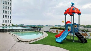A rooftop pool area with a slide and play structure. - Apartemen Patra Land Urbano By Abdihome (Bekasi)
