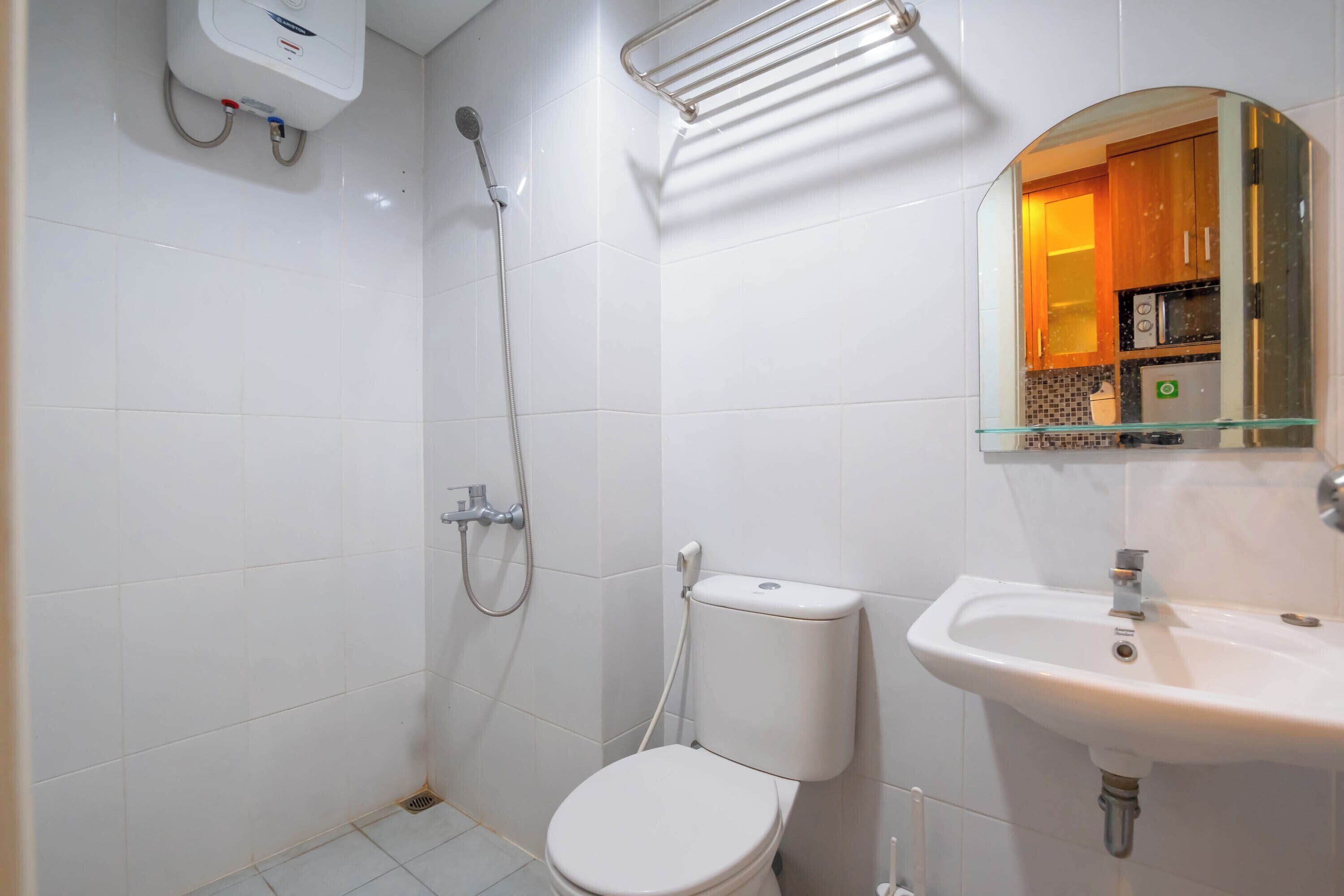 Un bany petit i modern amb vàter, plat de dutxa amb envàs de vidre, rentapel i mirall.