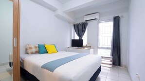 A bedroom with a large bed, a desk with a computer, an air conditioning unit, and a window with curtains. - Apartemen Patra Land Urbano By Abdihome (Bekasi)