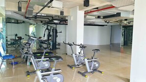 A gym with exercise equipment, including treadmills and stationary bikes, and a mirrored wall. - Apartemen Patra Land Urbano By Abdihome (Bekasi)