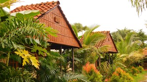 A traditional house with a tiled roof surrounded by lush tropical vegetation. - Gram Bangla Retreat (Alipur)