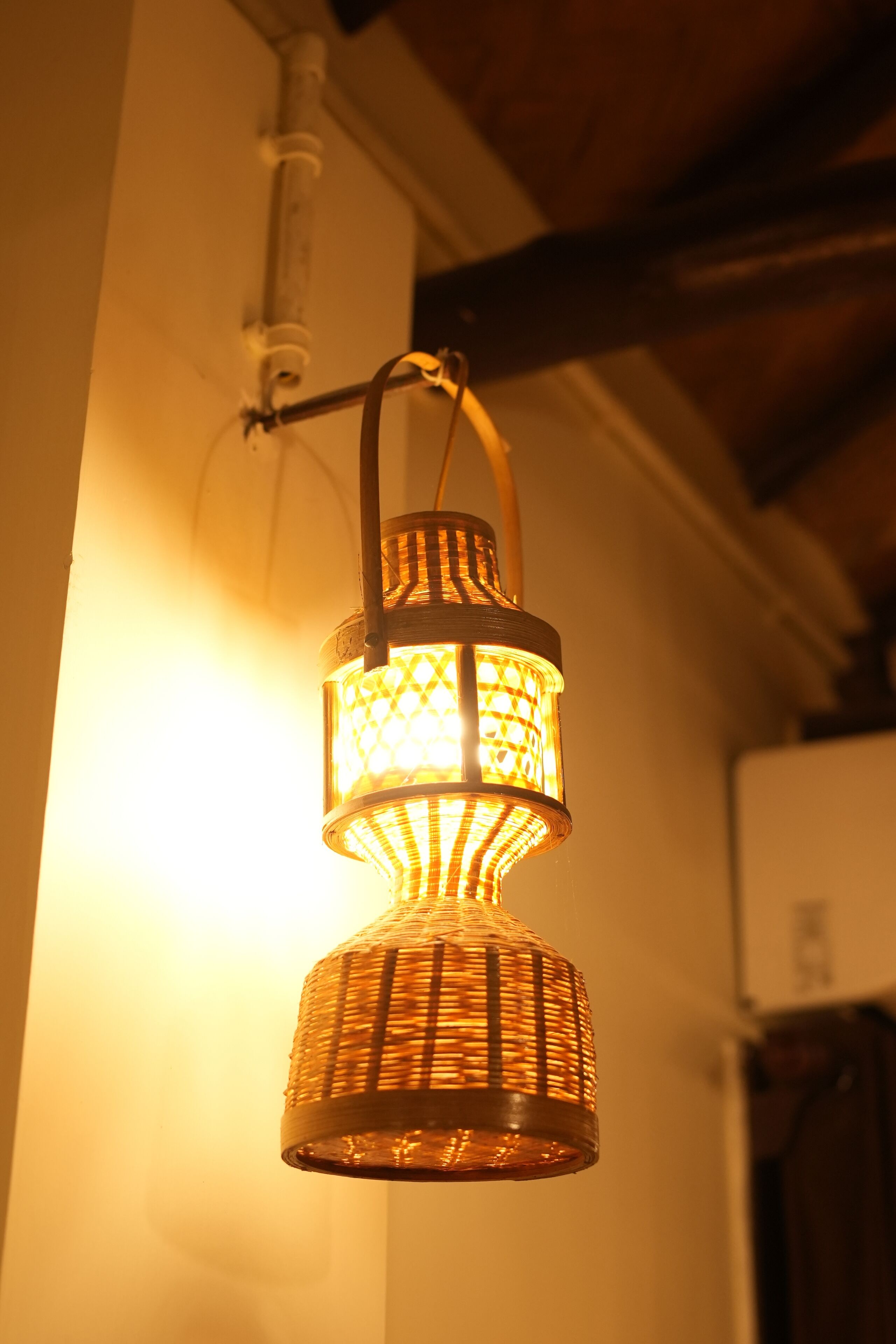 A hanging woven light fixture with a warm glow.
